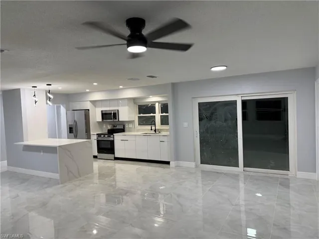 Kitchen featuring stainless steel appliances, white cabinets, a textured ceiling, decorative light fixtures, and ceiling fan