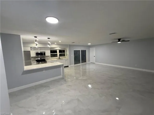 Unfurnished living room featuring baseboards and a ceiling fan