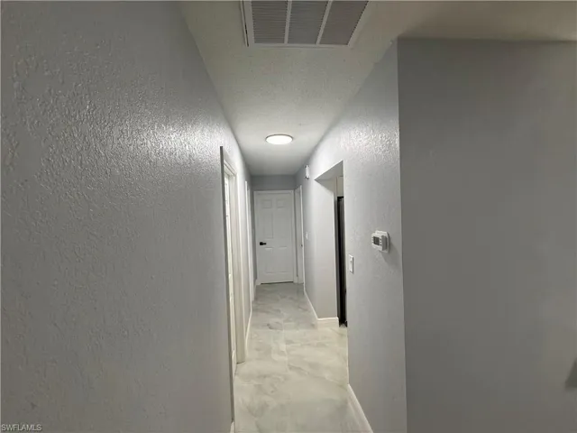Hall with a textured wall and a textured ceiling