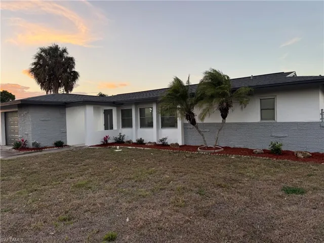 Single story home with a garage, stucco siding, a lawn, and roof with shingles
