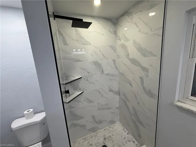 Bathroom with a stall shower and a textured wall