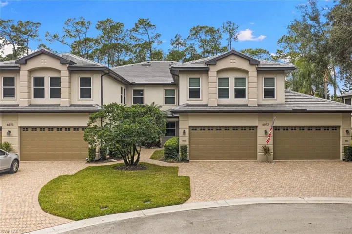 View of front of property featuring stucco siding, a garage, decorative driveway, and a tiled roof