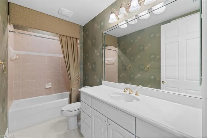Full bath featuring shower / bath combination with curtain, vanity, light tile patterned flooring, and wallpapered walls