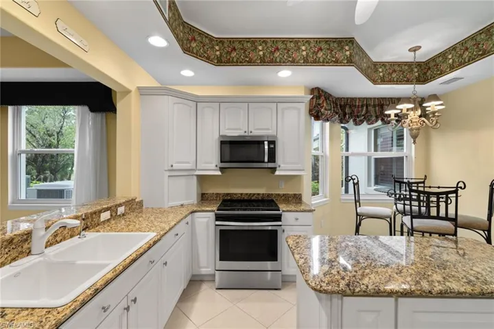 Kitchen with appliances with stainless steel finishes, white cabinets, decorative light fixtures, dark stone countertops, and recessed lighting