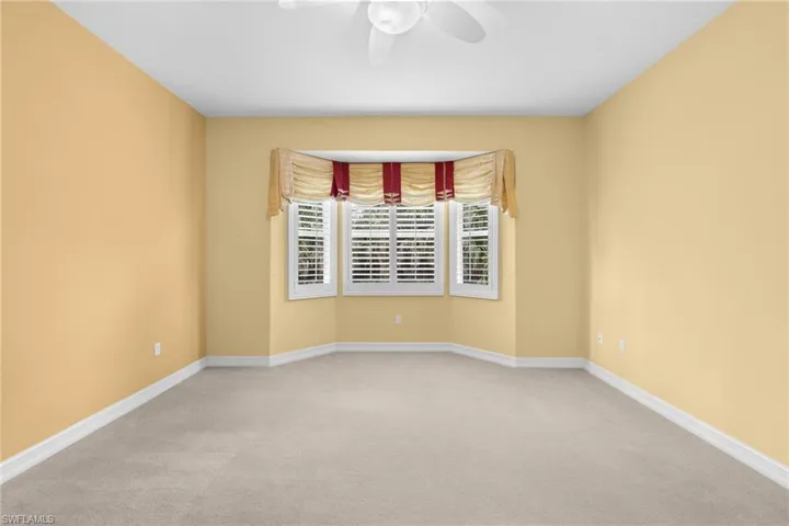 Carpeted spare room with baseboards and ceiling fan
