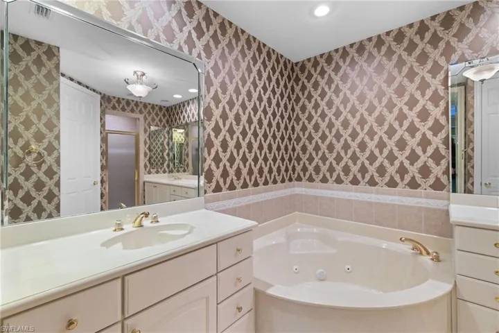 Bathroom featuring vanity, recessed lighting, a jetted tub, and wallpapered walls