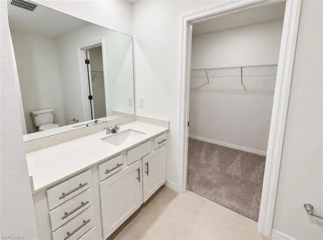 White vanity with a light-toned countertop, integrated sink, and chrome faucet