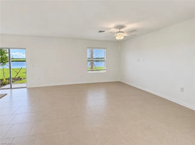 Neutral tone tile flooring, white walls, ceiling fan, sliding glass door, and a single window with blinds