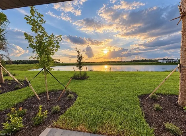 Manicured lawn with mature landscaping and a serene waterfront backdrop