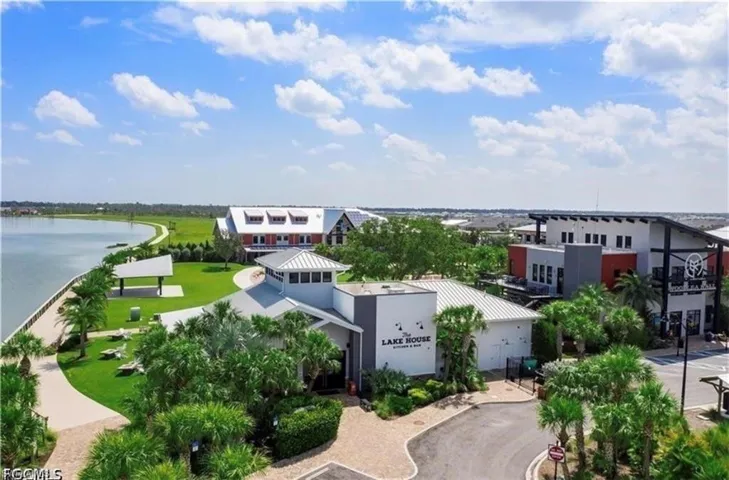 Lakefront property featuring a paved walking path, mature palm trees, and a covered outdoor structure