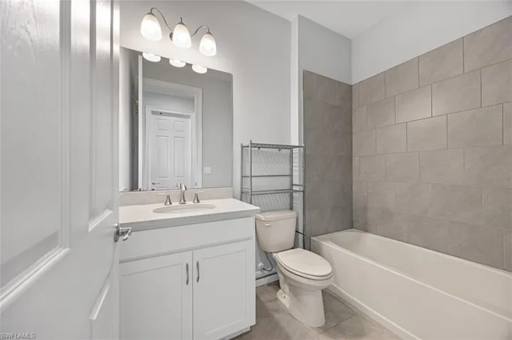 Bathroom featuring vanity,  shower combination, and light tile patterned flooring