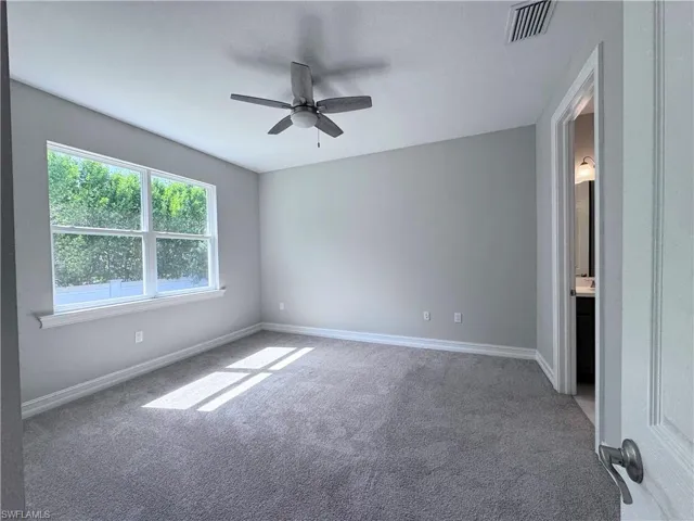 Carpeted spare room with baseboards and ceiling fan