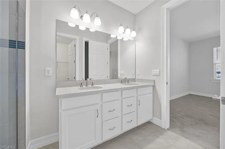 Bathroom with light tile patterned flooring and double vanity