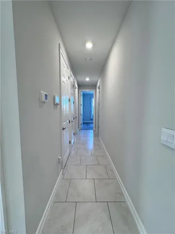 Corridor with light tile patterned floors and baseboards