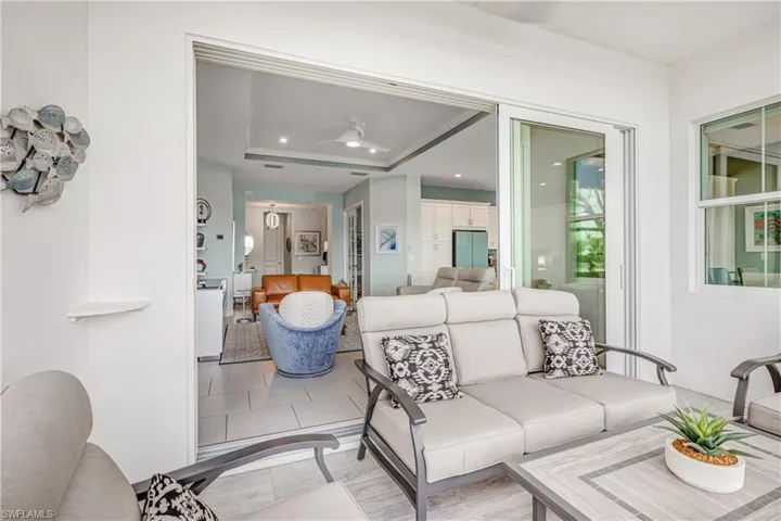 Living room with a raised ceiling, ceiling fan, recessed lighting, and light tile patterned floors