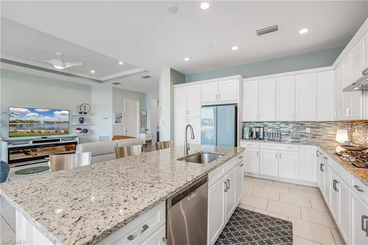 Kitchen featuring white cabinets, stainless steel appliances, ornamental molding, recessed lighting, and a raised ceiling