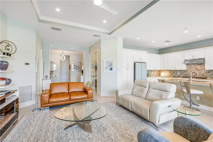 Living room featuring ceiling fan, a raised ceiling, ornamental molding, and recessed lighting