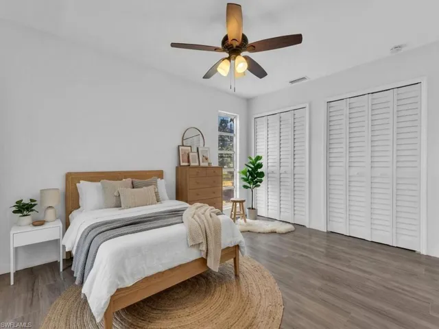 Bedroom featuring two closets, wood finished floors, and a ceiling fan - Virtually Staged
