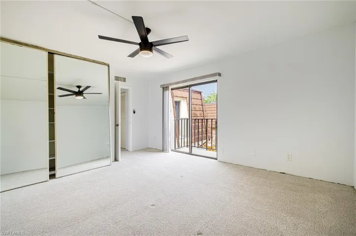 Room featuring a sliding glass door to an exterior balcony, a ceiling fan with integrated lighting, and a mirrored sliding closet door