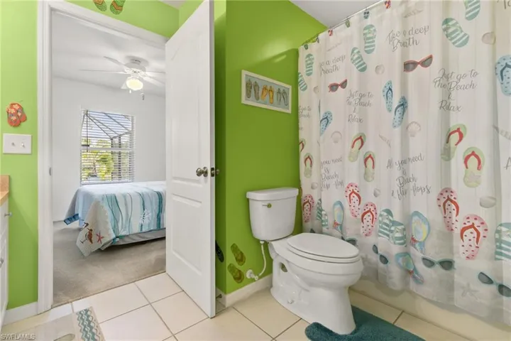 Bathroom featuring vanity, toilet, tile patterned flooring, and ceiling fan