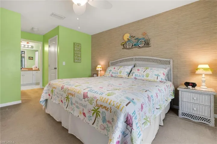 Bedroom with ceiling fan, connected bathroom, and light colored carpet