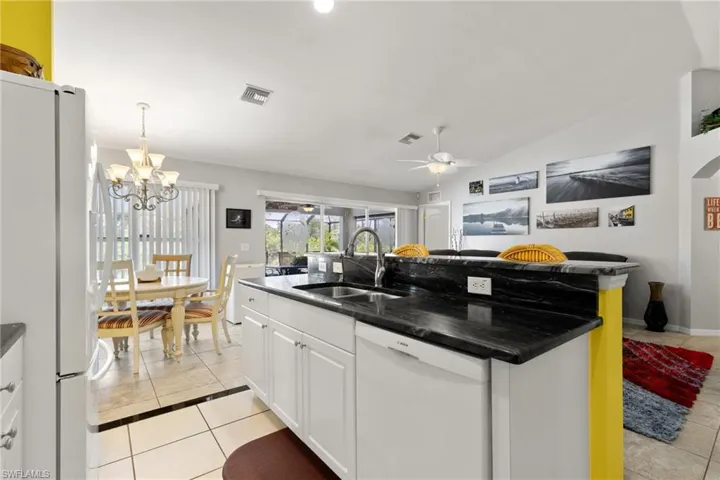 Kitchen with white appliances, sink, light tile patterned flooring, and white cabinetry