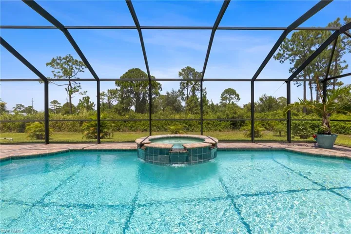 View of pool with a lanai and an in ground hot tub