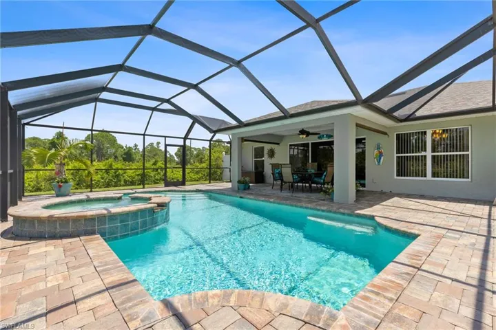 View of pool with an in ground hot tub, a patio, glass enclosure, and ceiling fan