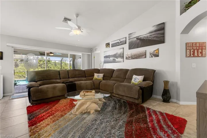 Tiled living room featuring vaulted ceiling and ceiling fan