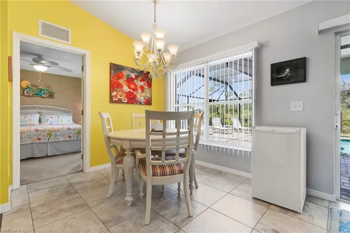 Tiled dining space with ceiling fan with notable chandelier