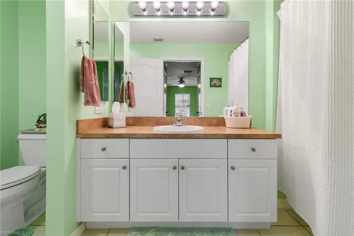 Bathroom with tile patterned floors, vanity, toilet, and ceiling fan