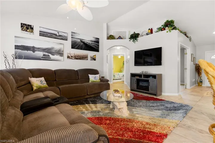 Tiled living room with ceiling fan and vaulted ceiling