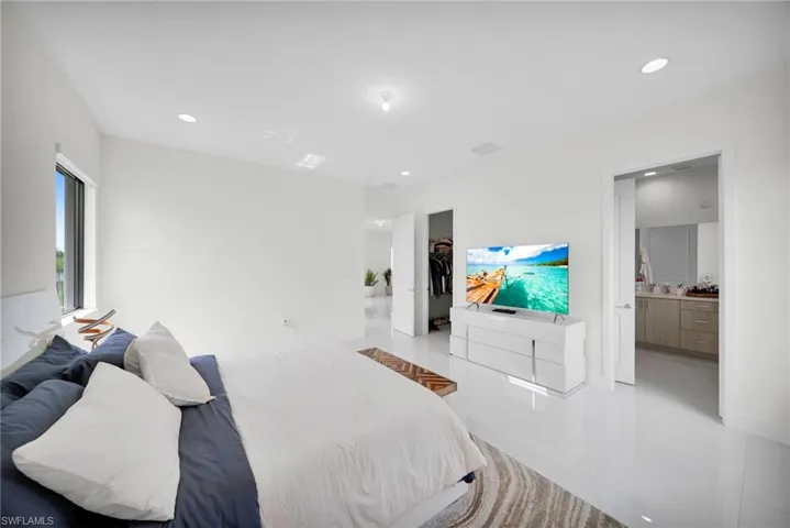Bright room featuring high ceilings, recessed lighting, expansive white tile flooring, and a large window offering natural light