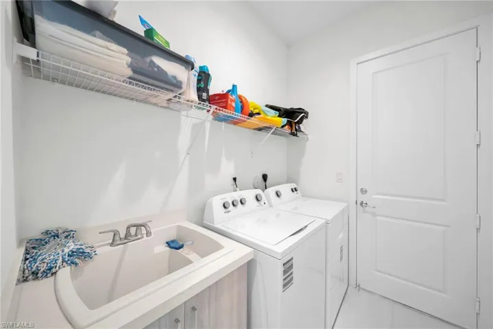 Dedicated laundry area featuring a utility sink, overhead wire shelving, and wood-finish cabinetry