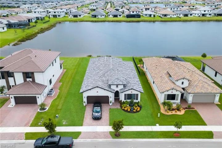 Traditional-style residence featuring a patterned paver driveway, an attached two-car garage, and a landscaped front yard