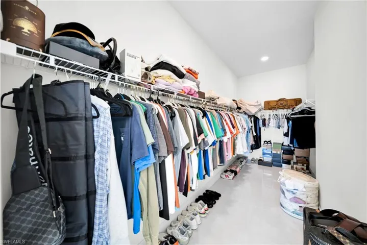 Spacious walk-in closet featuring white wall finishes, built-in wire shelving, and overhead recessed lighting
