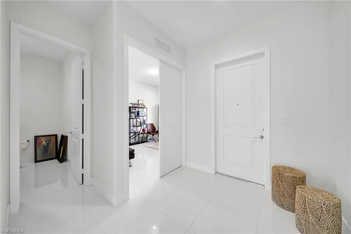 Entryway featuring white tile flooring, white walls, and bright overhead lighting