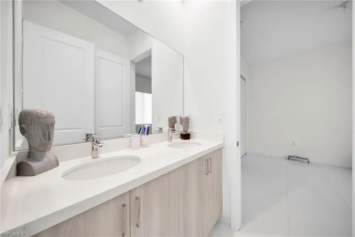 Dual vanity featuring light wood-finish cabinetry, integrated sinks, and polished chrome faucets