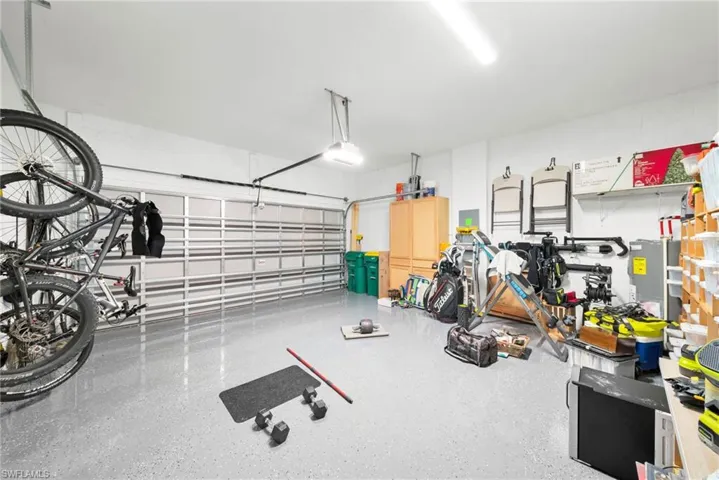 Spacious garage featuring an epoxy-coated concrete floor, overhead lighting, and built-in wall shelving