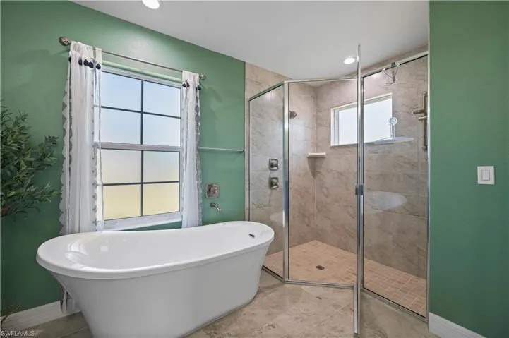 Bathroom featuring a stall shower, baseboards, and a freestanding bath