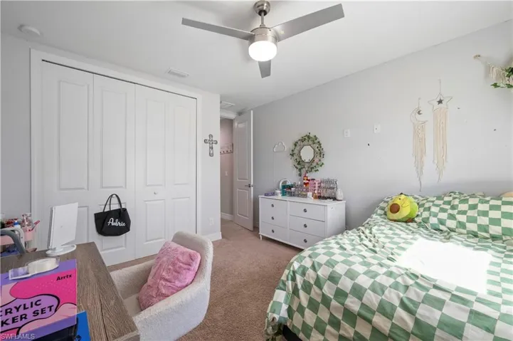 Bedroom with carpet flooring, a closet, visible vents, and a ceiling fan