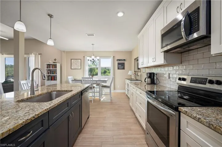 Kitchen featuring a sink, stainless steel appliances, white cabinetry, a chandelier, and tasteful backsplash