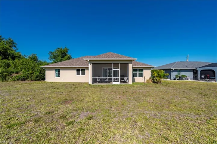 Rear view of property featuring a sunroom, a yard, and stucco siding