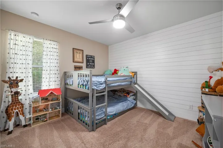 Bedroom with a ceiling fan, wooden walls, and carpet