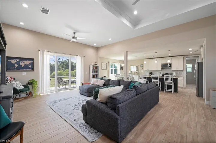 Living area with plenty of natural light, light wood-type flooring, visible vents, and ceiling fan