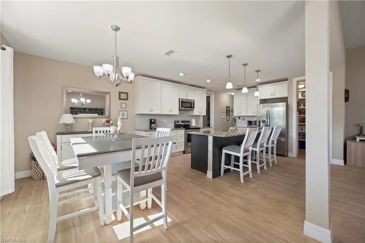 Dining area featuring a chandelier, light wood finished floors, baseboards, and visible vents