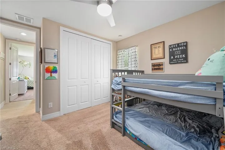 Bedroom with carpet flooring, a ceiling fan, a closet, visible vents, and baseboards