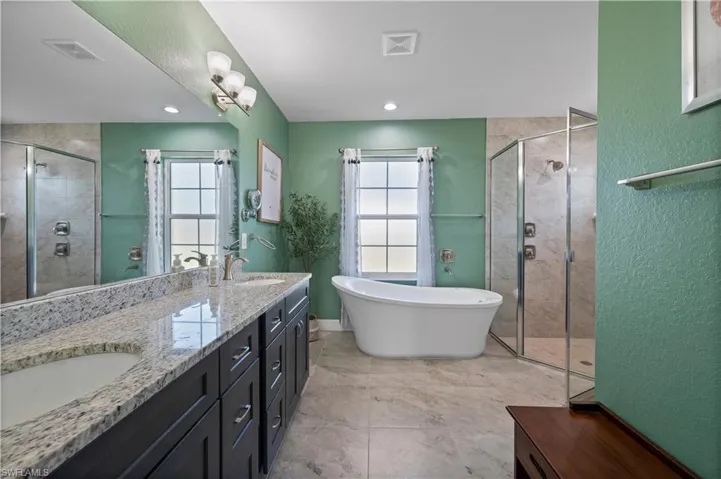 Full bathroom with a sink, double vanity, a stall shower, and a freestanding bath