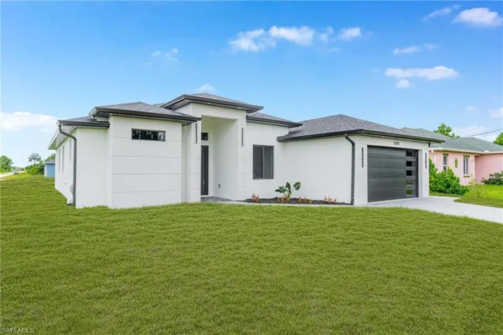 Prairie-style home featuring an attached garage, driveway, a front yard, and stucco siding