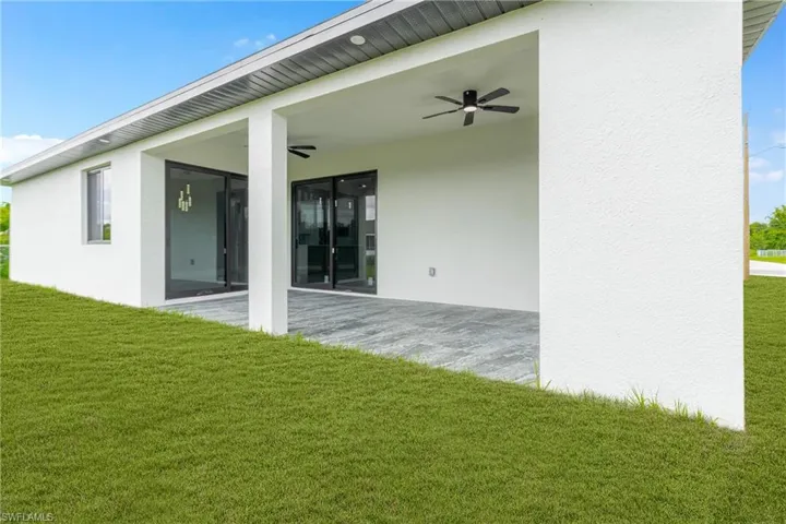 Back of house with ceiling fan, a patio area, a yard, and stucco siding